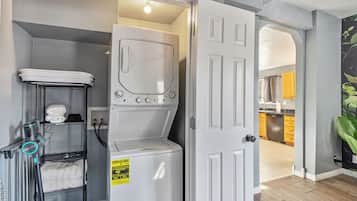 Un cuarto de lavandería con lavadora y secadora apiladas, un tendedero y un calentador de agua.