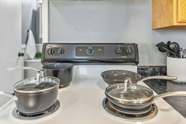 A kitchen with a stove, pots, and a utensil holder.