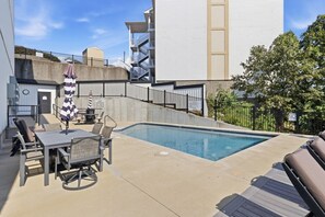 A swimming pool with a sun umbrella, lounge chairs, and a table with chairs. - The Golden Hour - Elevator & Main Channel Views! (Osage Beach)