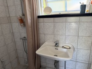 A bathroom with a white sink, a shower, and a window with a view. - "Andrina" - 490m from the sea by Interhome (Sæby)