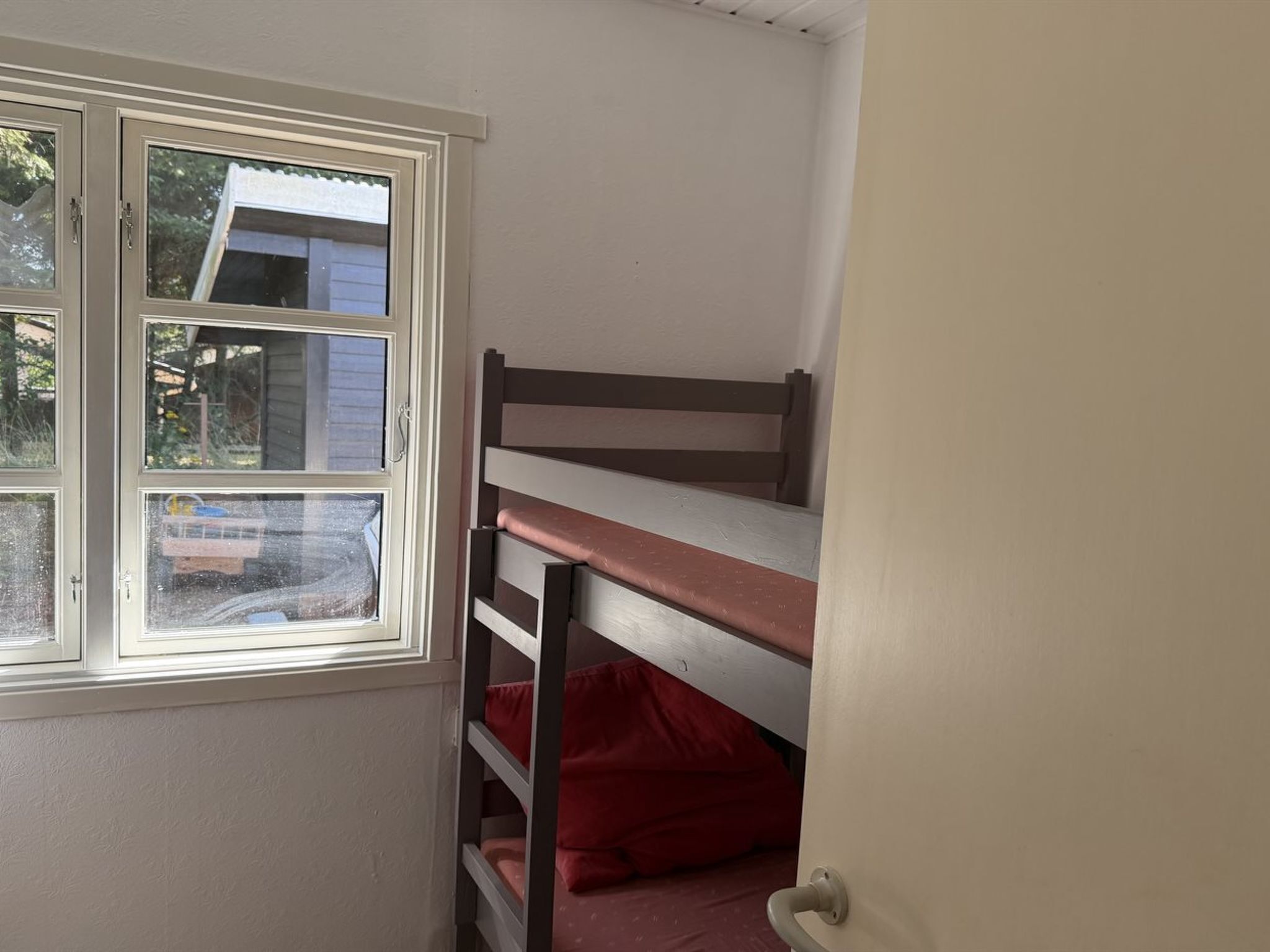 A room with a bunk bed, a window, and a door.