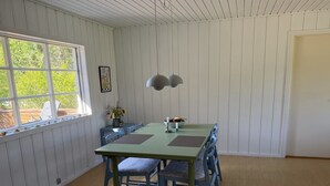 Ruokailutila, jossa on pöytä ja tuolit, ikkuna, josta on näkymä, ja katossa oleva valaisin.
