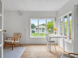 Ein Zimmer mit Holzboden, weißen Wänden, einem Fenster, einem Tisch, zwei Stühlen und einem Teppich.