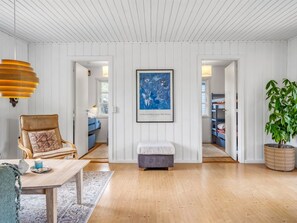 A spacious living room with wooden floors, a comfortable chair, a small table, and a large potted plant. - "Andrina" - 350m from the sea by Interhome (Sæby)