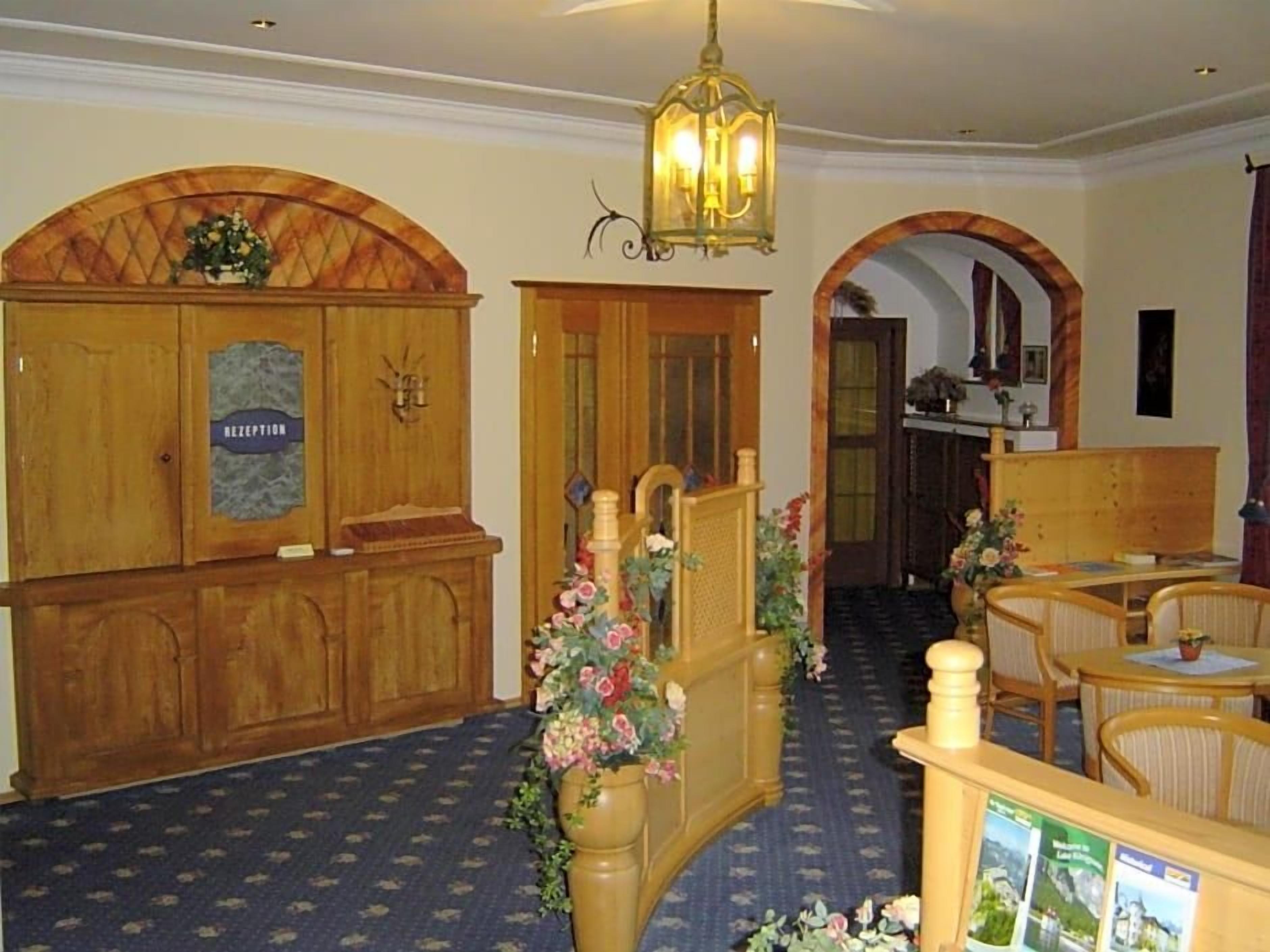 Een receptie met een houten balie, een kroonluchter en een vloerbedekking in blauw.