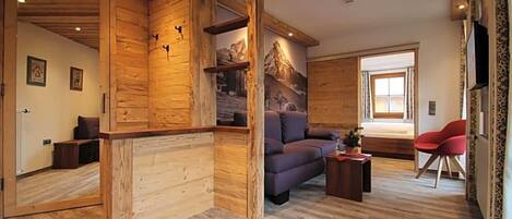 Un interior de madera con un sofá, una silla roja y una ventana.