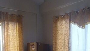 Quarto de hotel com uma cama, uma mesa de madeira com um menu e um frigorífico.