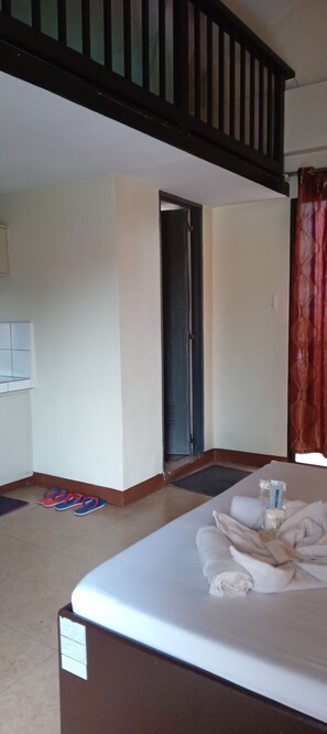 Een hotelkamer met een bed, een deur, een raam met gordijnen en een klein tafeltje met spullen erop.