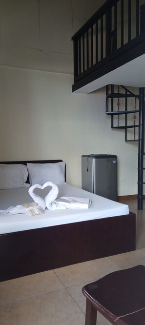 Een hotelkamer met een bed, een kleine koelkast en een trap.