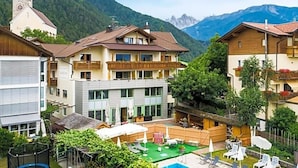A hotel with a pool, outdoor seating, and a mountain backdrop. - Wandergasthof Stern (Funes)