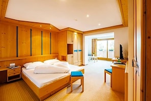 A hotel room with a wooden bed, a desk, a chair, and a view of the outdoors. - Wandergasthof Stern (Funes)