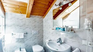 A bathroom with a bidet, toilet, sink, and a mirror with a towel rack. - Wandergasthof Stern (Funes)