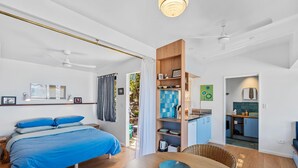 Ein Schlafzimmer mit Bett, Esstisch mit Schüssel, einer Küchenzeile und einem Badezimmer.