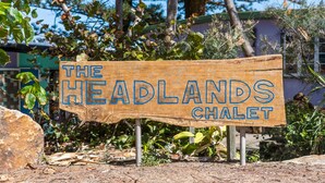 Un letrero de madera con el texto 'THE HEADLANDS CHALET' que indica un lugar.