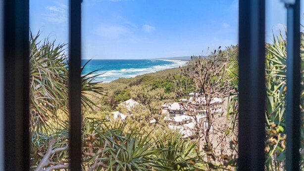 Eine Küstenansicht bei klarem Himmel, mit Vegetation und Gebäuden.