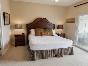 A bedroom with a large bed, two bedside tables with lamps, a window with a view, and a door. - Waterfront Condo w/ Boat Docking & Fishing (Foley)