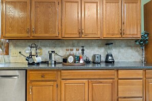 Eine Küche mit Holzschränken, einer Kaffeemaschine, einem Mixer und verschiedenen Küchengeräten.