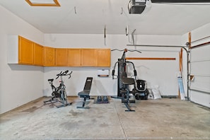 Eine Garage mit einem stationären Fahrrad, einer Sitzbank und einer Gewichtshebemaschine.