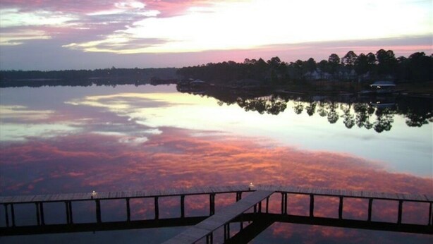 A calm lake at sunset with a wooden dock in the foreground. - Waterfront Condo w/ Boat Docking & Fishing (Foley)
