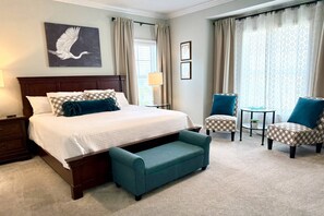 Ein Hotelzimmer mit einem großen Bett, einem Schreibtisch, zwei Stühlen, einem kleinen Tisch und einer Bank.