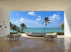 Une chambre avec vue sur l’océan, un bateau et des palmiers.