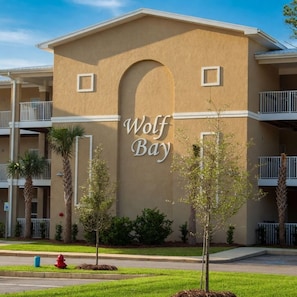A building with a sign reading 'Wolf Bay' and balconies. - Waterfront Condo w/ Boat Docking & Fishing (Foley)