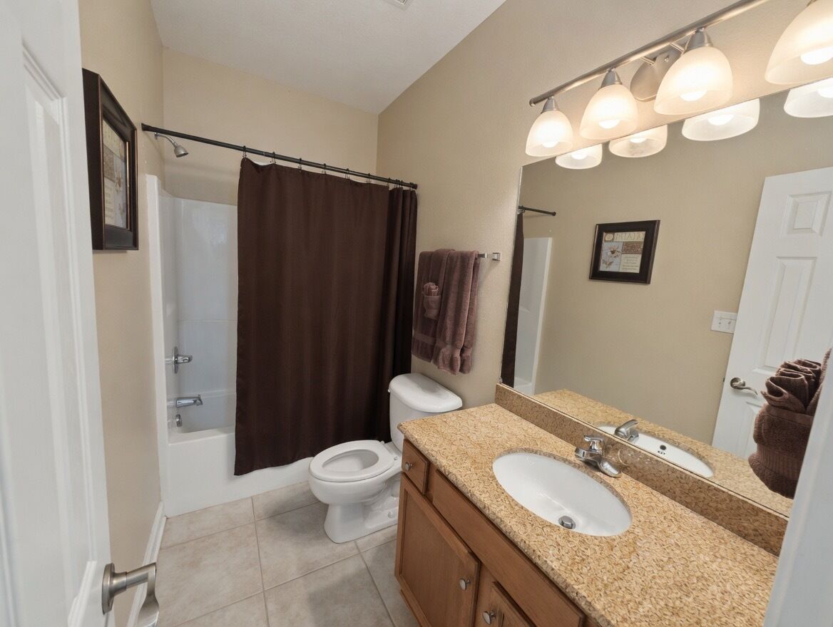 A bathroom with a bathtub, toilet, sink, and mirror.