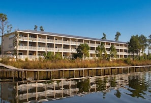Ein mehrstöckiges Hotel mit Balkonen, einem Anlegesteg und einem Gewässer im Vordergrund.