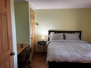 A bedroom with a bed, a desk, and a chair.