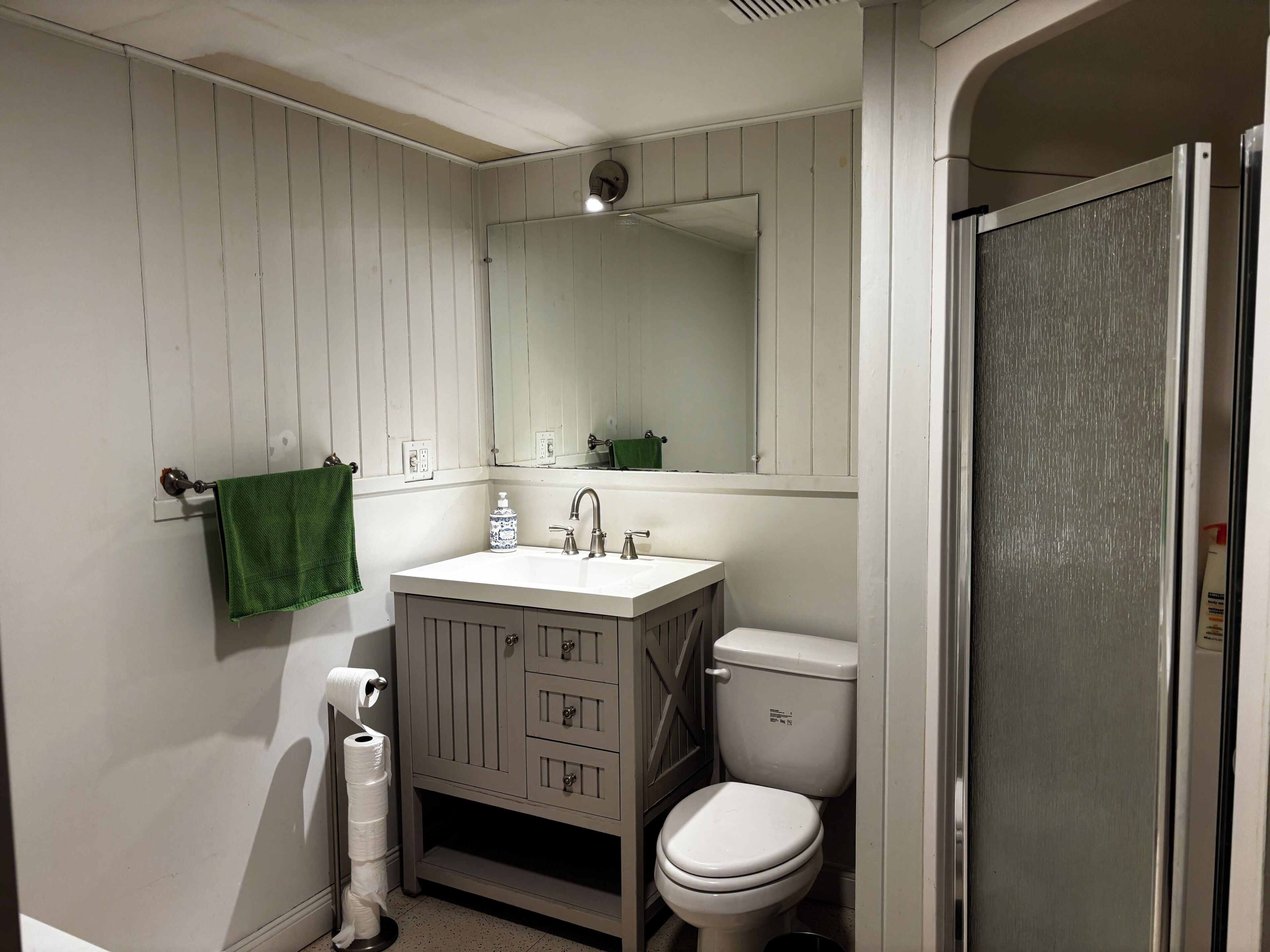 A bathroom with a white sink, a toilet, a mirror, and a towel rack.