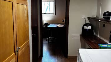 A narrow hallway with wooden flooring, a washing machine, and a window providing natural light.