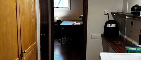 A narrow hallway with wooden flooring, a washing machine, and a window providing natural light.