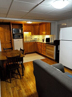 A compact kitchen with wooden cabinets, a microwave, a toaster, and a refrigerator.