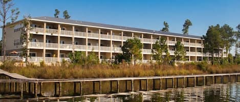 A multi-story hotel with balconies, a dock, and a body of water in the foreground.