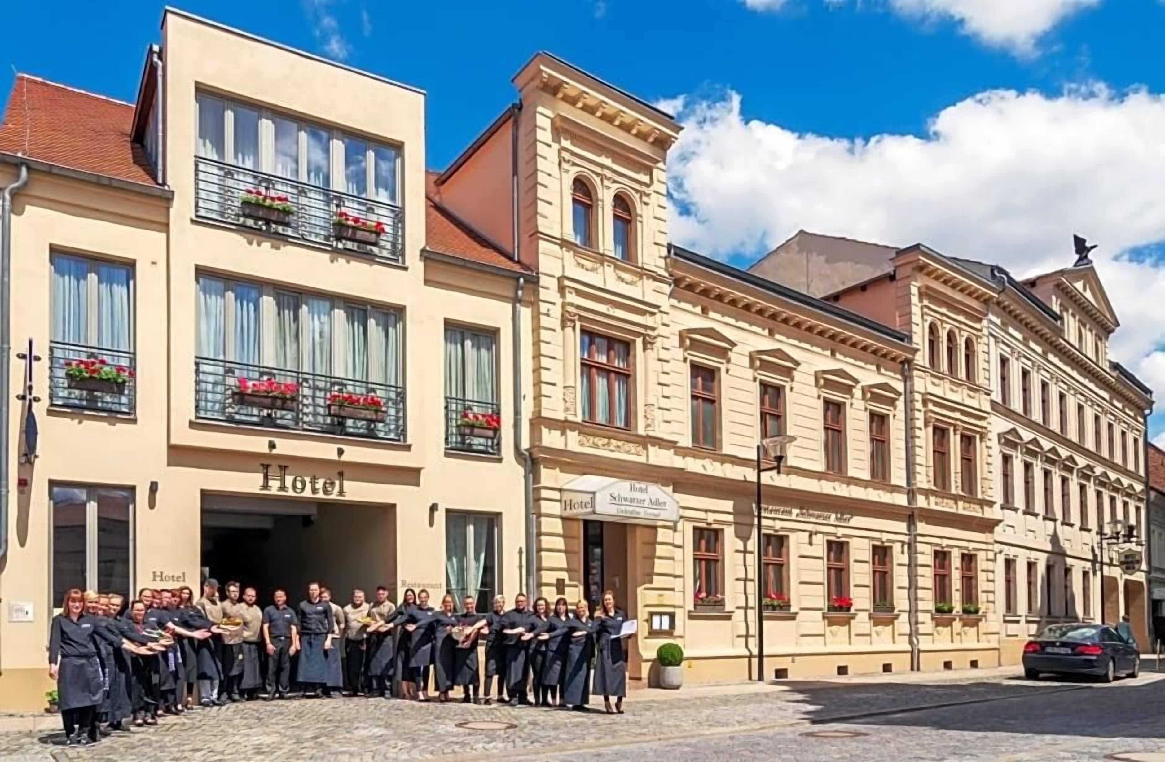 Ein Hotel mit einer Gruppe von Personen vor der Fassade, Straßenansicht und einem Gebäude mit dem Schild 'Hotel'.