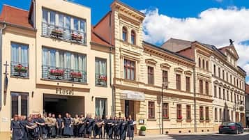 Ein Hotel mit einer Gruppe von Personen vor der Fassade, Straßenansicht und einem Gebäude mit dem Schild 'Hotel'.