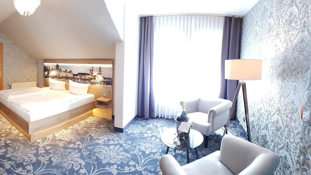 Habitación de hotel con cama, escritorio, silla, mesita y lámpara.