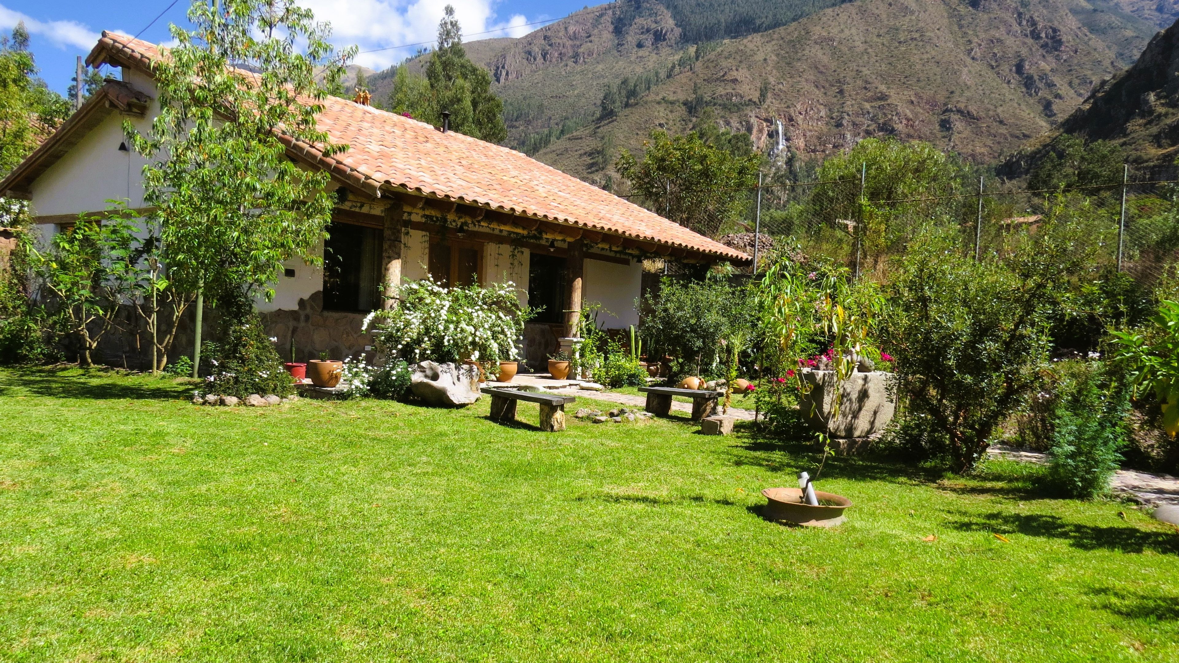 A house with a tiled roof, surrounded by a well-maintained lawn and various potted plants.