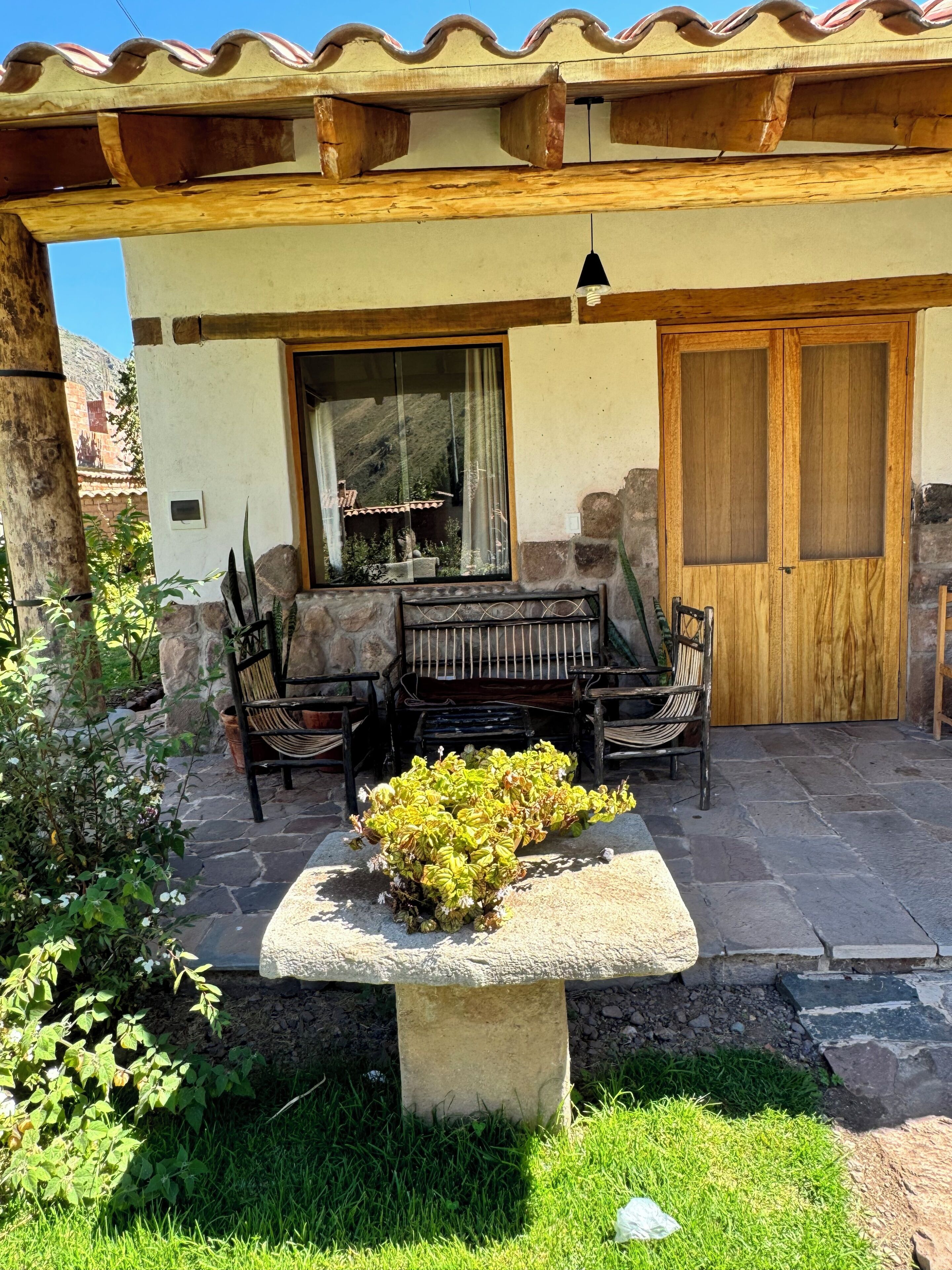A patio with a stone table, chairs, and a small garden.