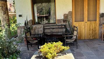 A patio with a stone table, chairs, and a small garden.