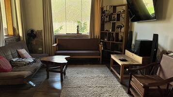 A living room with a sofa, a coffee table, a TV, and a bookshelf.