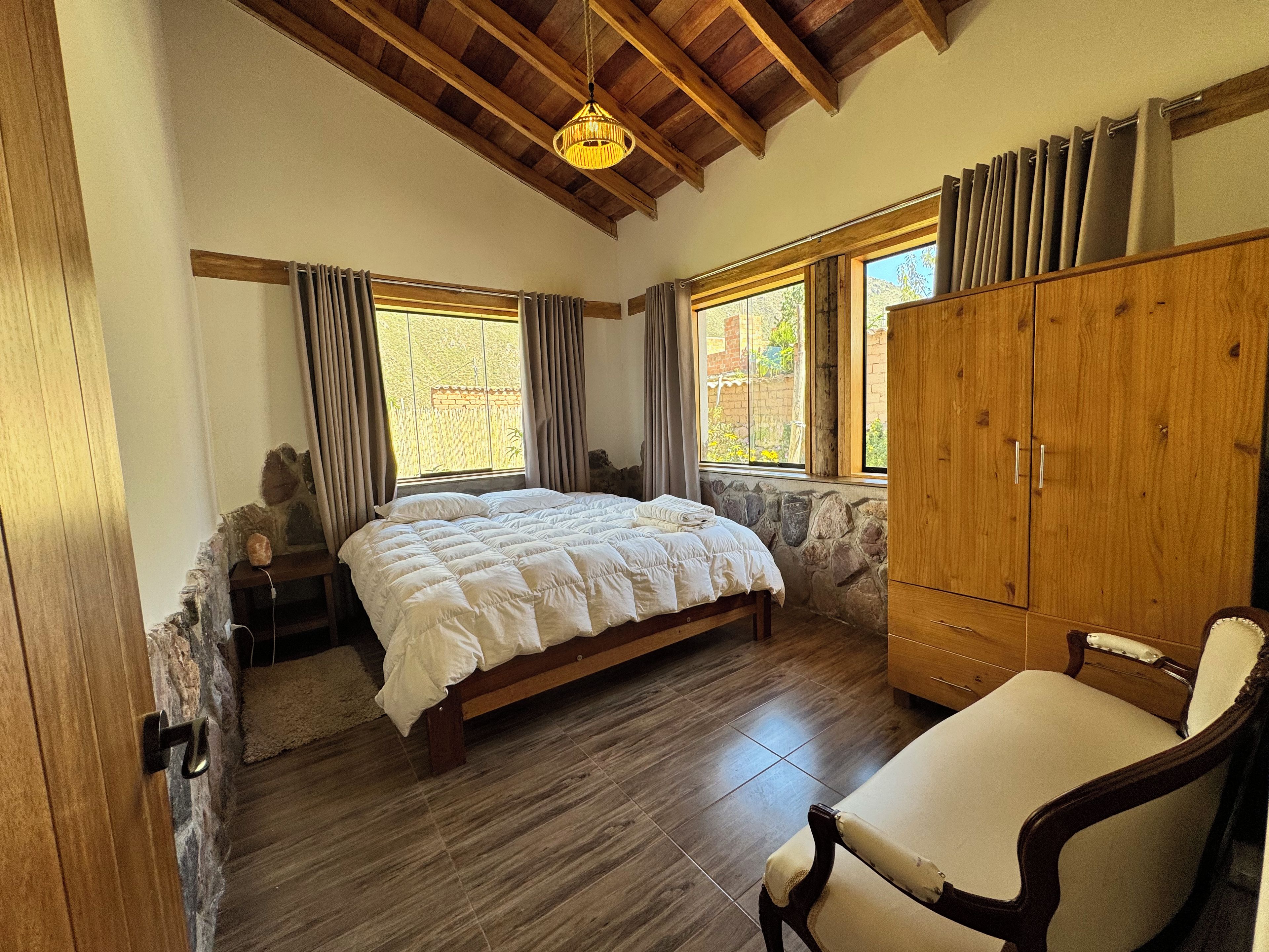Un dormitorio con cama, armario de madera y una silla.