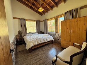 A bedroom with a bed, wooden wardrobe, and a chair.