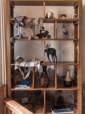 Una estantería de madera con diversos objetos decorativos, incluyendo un perro de peluche, una cabeza de venado, un jarrón y un libro.