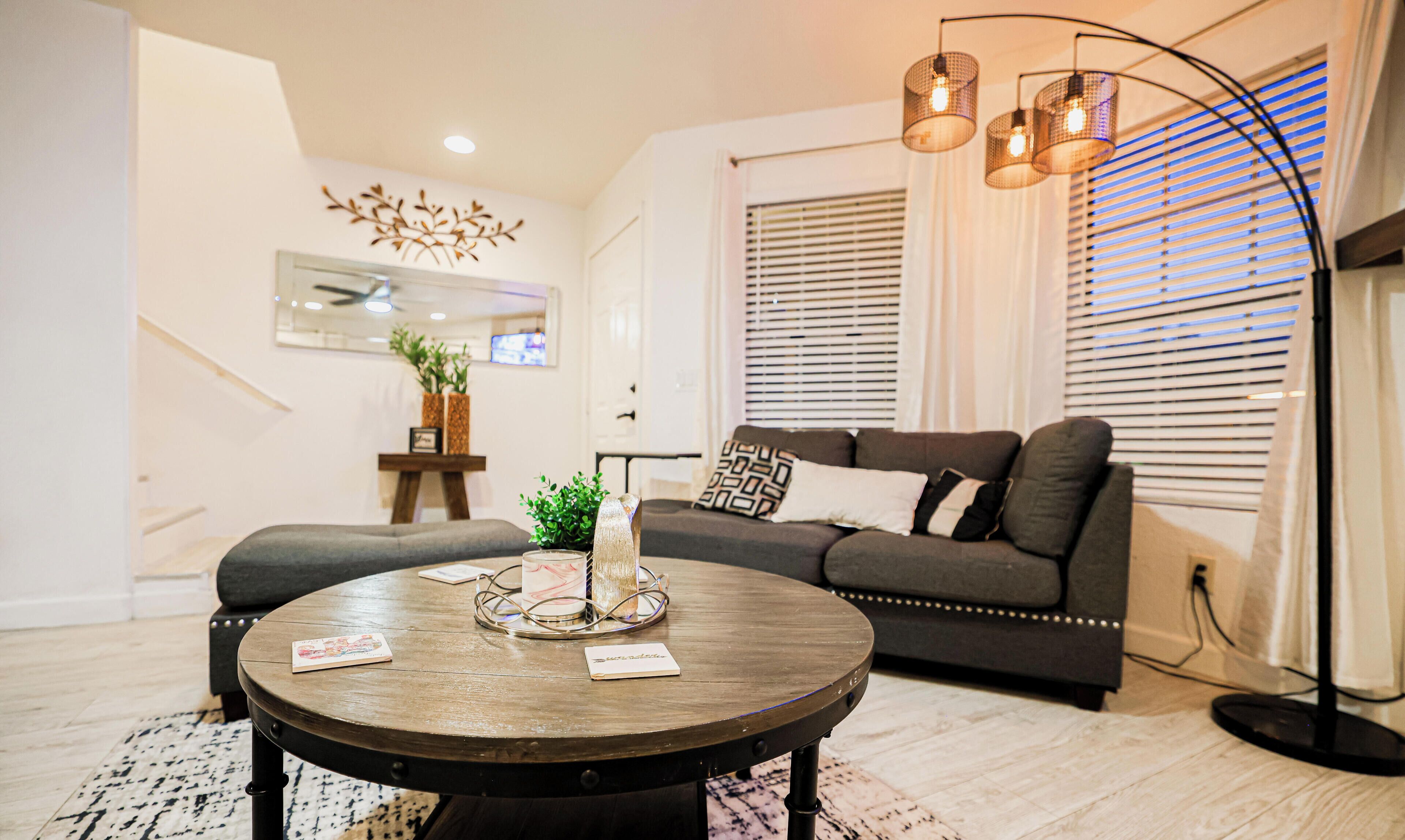 A modern living room with a round coffee table, a sofa, and a decorative wall piece.