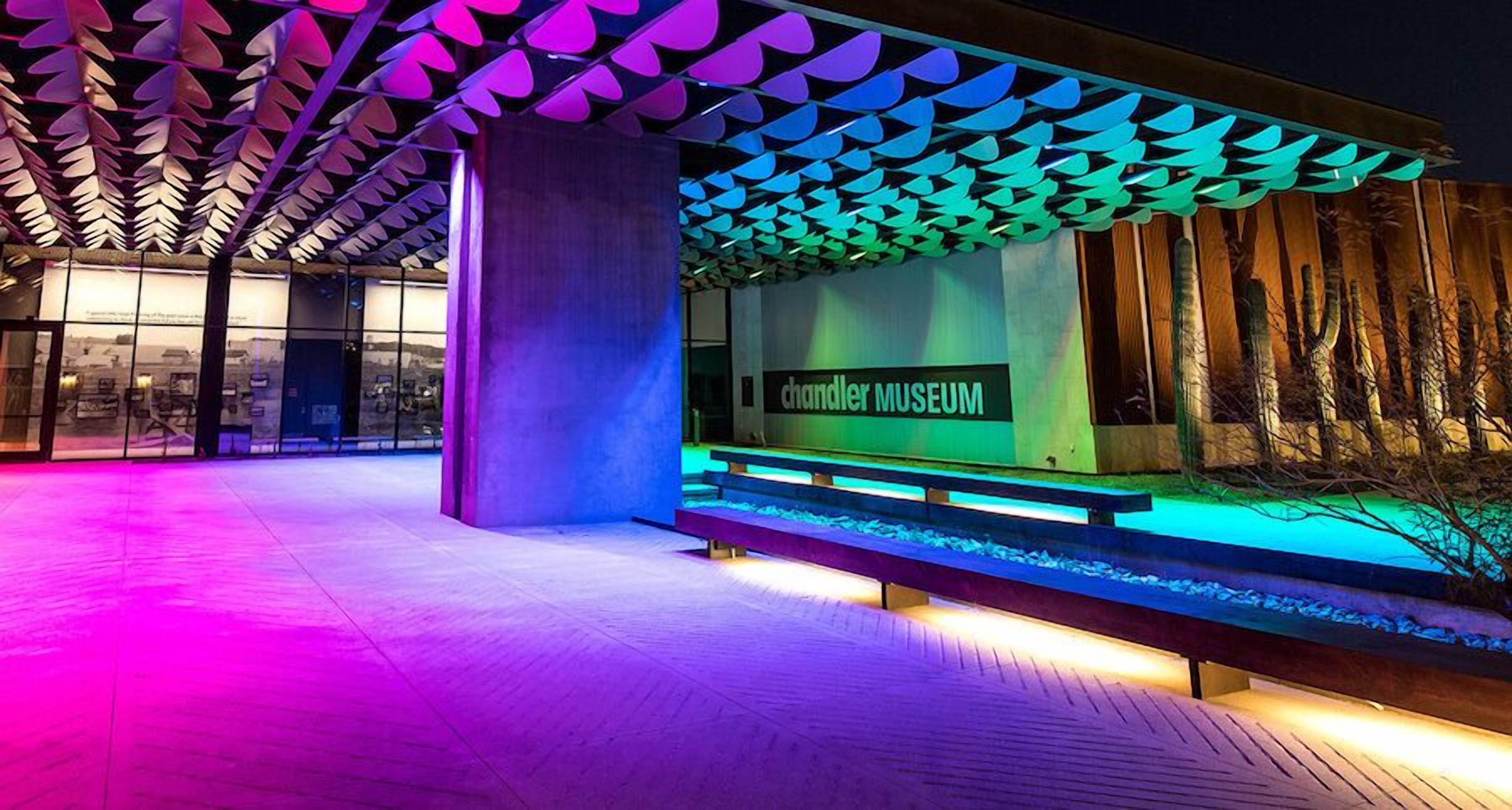 An outdoor area with a modern building labeled 'chandler museum,' featuring a unique ceiling design and a bench.