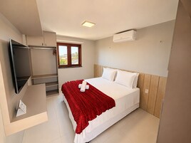 Un dormitorio con cama, televisión, ventana y aire acondicionado.