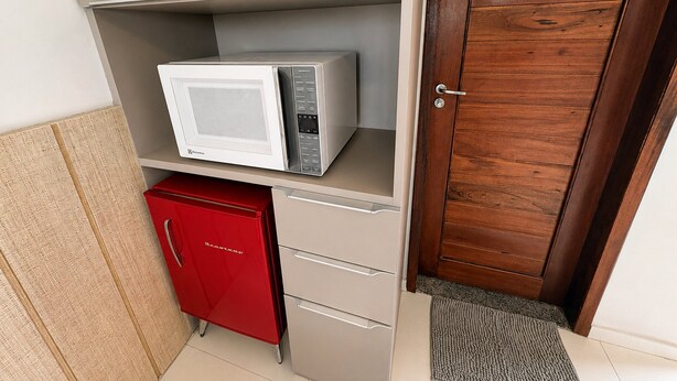 Una kitchenette equipada con microondas, un refrigerador rojo y una puerta de madera.