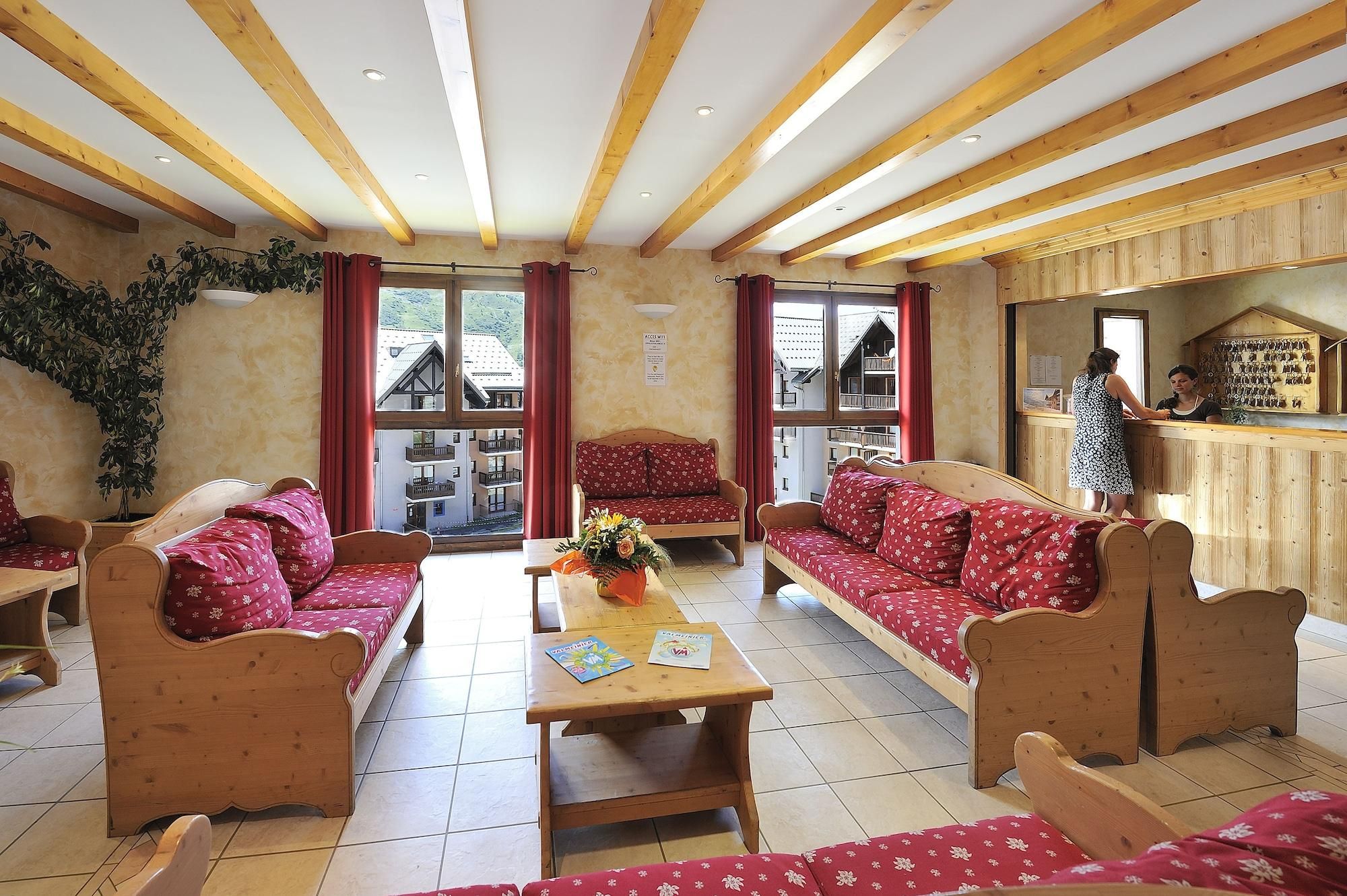 Un hall d’hôtel avec des meubles en bois, un comptoir d’accueil et de grandes fenêtres.