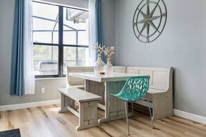 A room with a wooden bench, a table, and a chair. There is a window with curtains, a wall-mounted compass, and a view of greenery outside. - Crystal River Waterfront w/ Dock, Pool & Manatees! (Crystal River)